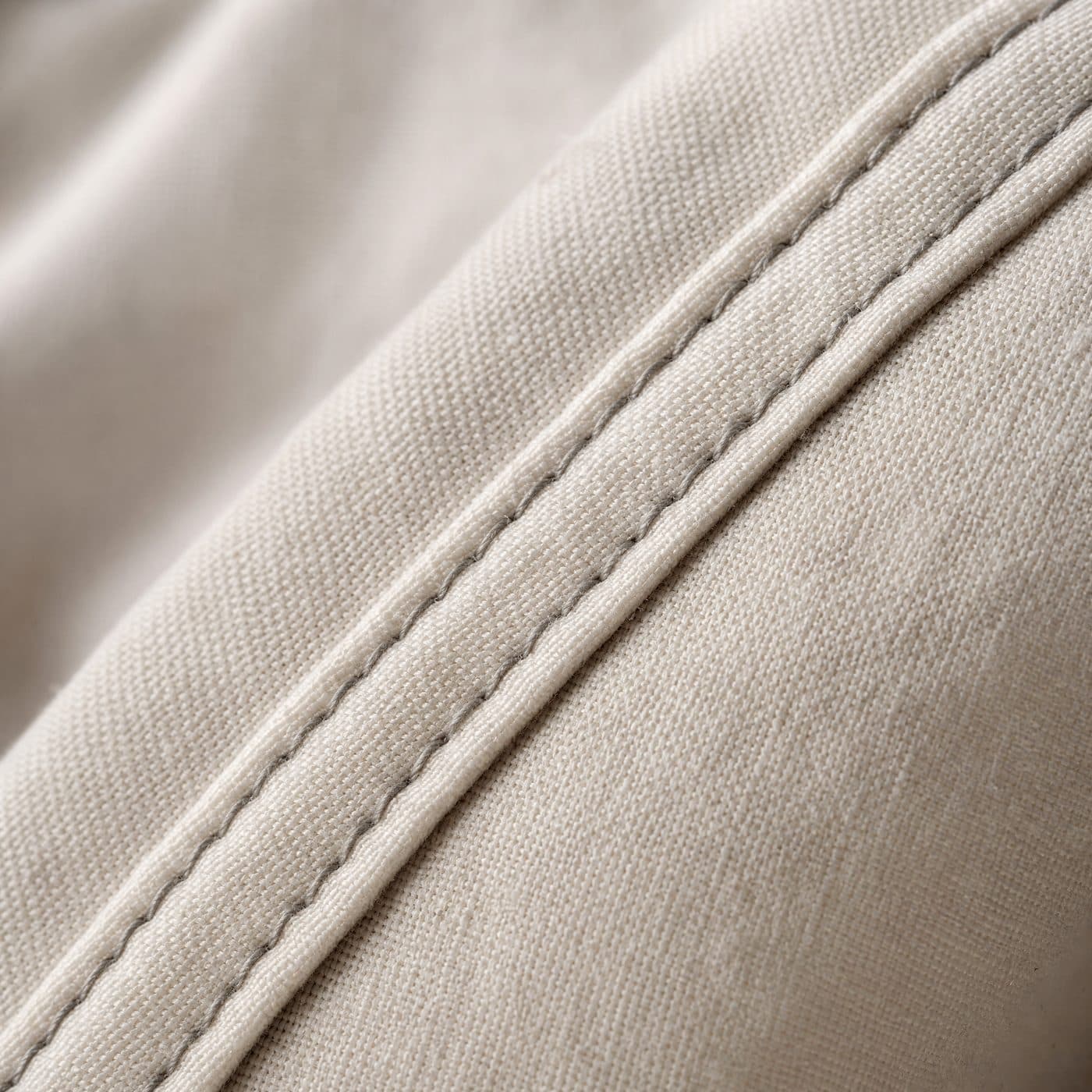 Extreme close-up of flat-felled stitching on the shoulder seam of a cotton shirt.